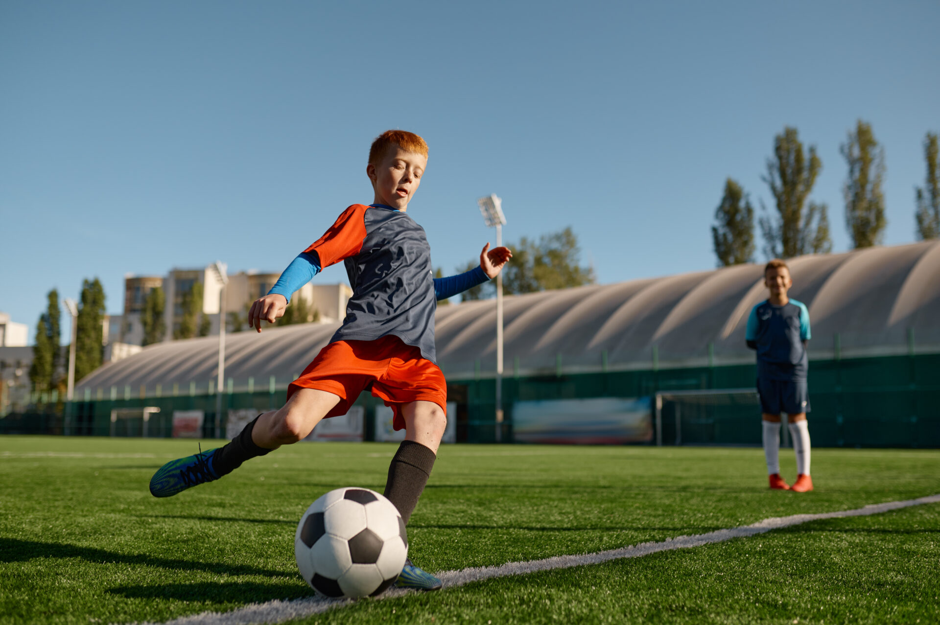 Boy playing football on field and kicking football