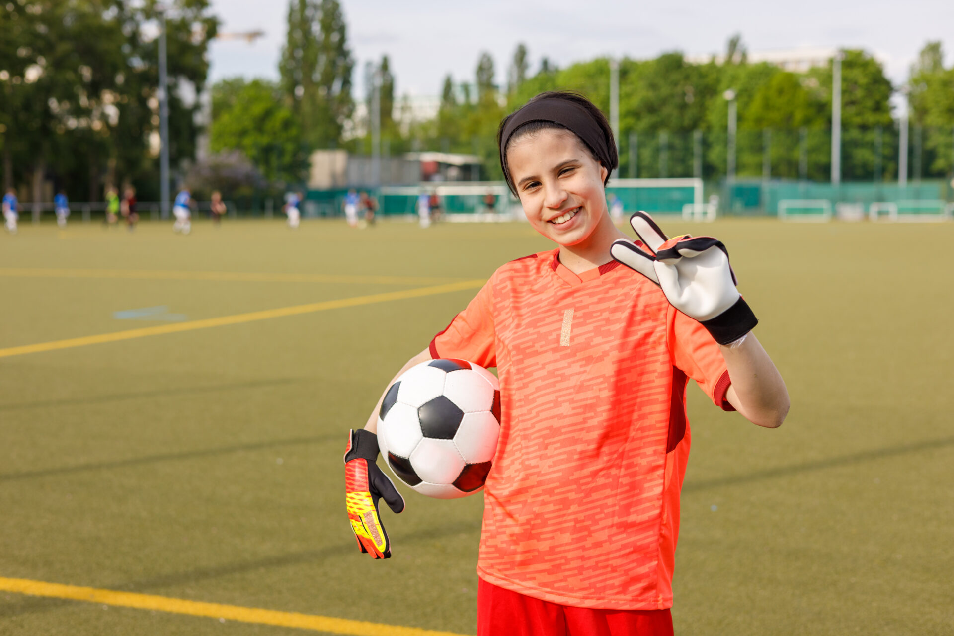 Girl with goalkeeper gloves holding football